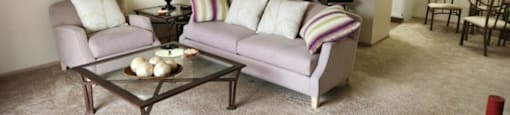 A living room with a grey couch and a glass coffee table.at Highlands of Heritage Woods, Copley, OH