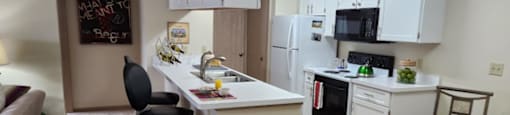 A kitchen with white cabinets and a black chair.at Highlands of Heritage Woods, Copley Ohio