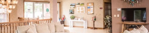 A living room with a white sofa, a glass coffee table, and a TV.at Highlands of Heritage Woods, Copley Ohio