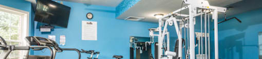 A gym with a variety of equipment including a treadmill, stationary bike, and weight bench.at Highlands of Heritage Woods, Ohio