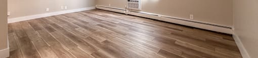 A room with wooden flooring and a window with blinds.