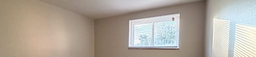 A room with wooden flooring and a window with blinds.