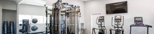 a spacious fitness room with cardio equipment and a flat screen tv at Paseo 51 Apartments, Glendale, 85302