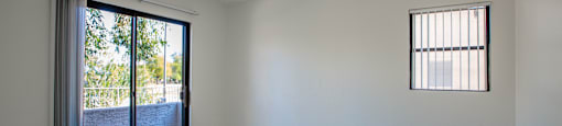 Empty room with a carpeted floor and a window with blinds.