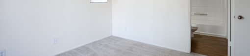 A room with a carpeted floor and a door leading to another room.