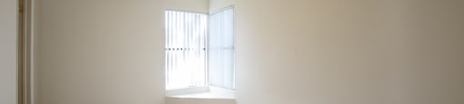 A room with a ceiling fan and a window letting in sunlight.