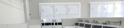 a large laundry room with white cabinets and appliances