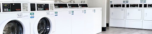 a large laundry room with white washers and dryers