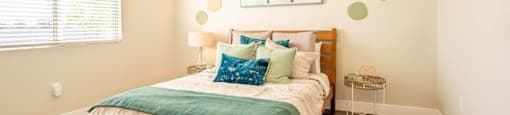 Model bedroom is furnished with a large bed and 2 nightstands at Village Greens of Queen Creek