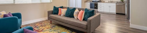 Furnished open floor plan living area has a couch and chairs in an apartment at Village Green of Queen Creek