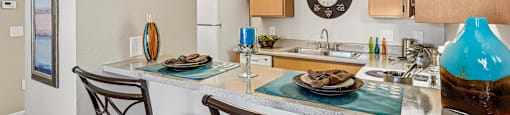 A kitchen with a table and two chairs.