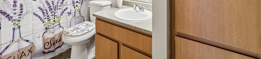 A bathroom with a shower curtain that says Home Sweet Home.