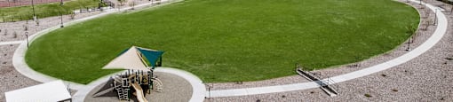 A playground with a green slide and a white canopy is surrounded by a circular path.