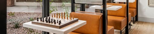 A chess board is set up on a table in front of a glass wall.