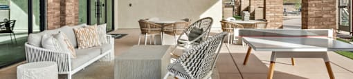 A modern outdoor patio with a white sofa, chairs, and a coffee table.