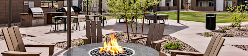 A fire pit sits in the middle of a patio surrounded by chairs.