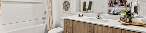 A bathroom with a white tub, sink, and toilet.