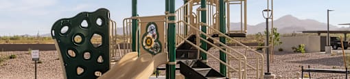 A playground with a yellow slide and a green umbrella.