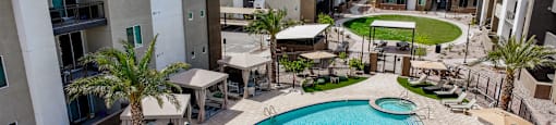 A pool surrounded by a fence and chairs in a courtyard.