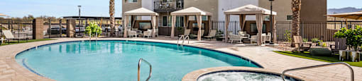A large swimming pool with a hot tub in front of a building.