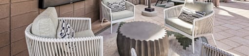 A patio with a white wicker chair and a round table.