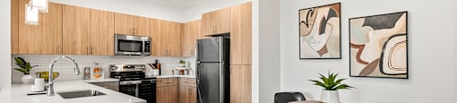A modern kitchen with a wooden counter and black chairs.