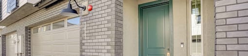 A house with a blue door and a grey garage door.