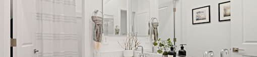A bathroom with a white sink and a white shower curtain.