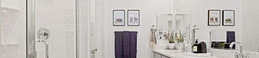 A bathroom with a glass shower door and a rug on the floor.