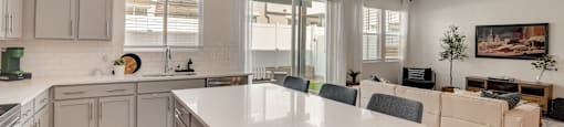 A modern kitchen with a large island and a living area with a couch.