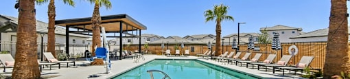 A pool surrounded by palm trees and lounge chairs.
