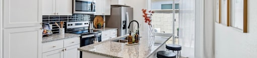 A kitchen with white cabinets and a granite countertop.