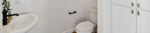 A white bathroom with a toilet, sink, and a towel rack.