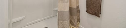 A white bathroom with a shower curtain and a towel hanging on a rack.