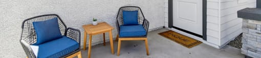 Two chairs and a small table are on a porch.