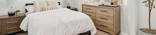 A bedroom with a bed, dresser, and a ceiling fan.