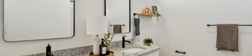A bathroom with a white toilet, a sink with a marble countertop, and a large mirror above the sink.