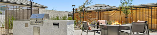 A patio with a fire pit and chairs.