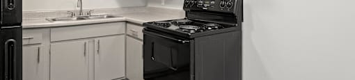 A black stove in a kitchen with white cabinets.