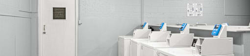 A white room with a door and a row of washing machines.