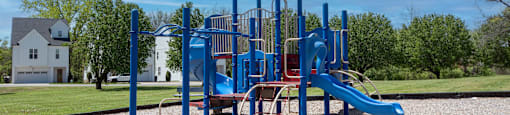 A playground with a blue slide and a green roofed structure.