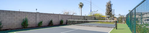 A tennis court with a green surface and a grey top.