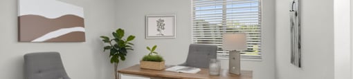 A room with a grey chair, a desk with a plant on it, and a painting on the wall.