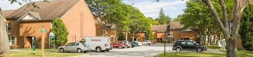 A street view of a residential area with cars parked and houses on both sides.