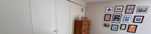 A bedroom with a bed, dresser, and a wall of pictures.