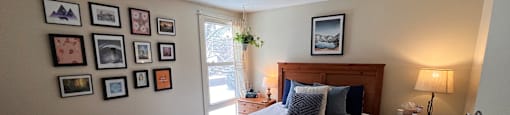 A bedroom with a bed, nightstand, and pictures on the wall.