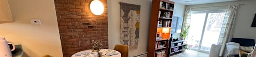 A living room with a brick wall and a round table with chairs.