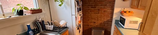 A kitchen with wooden cabinets and a brick wall.