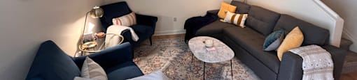 A living room with a couch, chair, and a table.