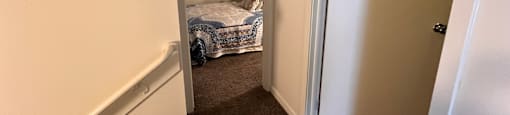 A bedroom with a bed and a carpeted floor.